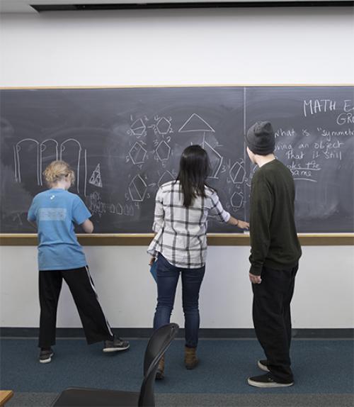  High school kids work at a chalkboard