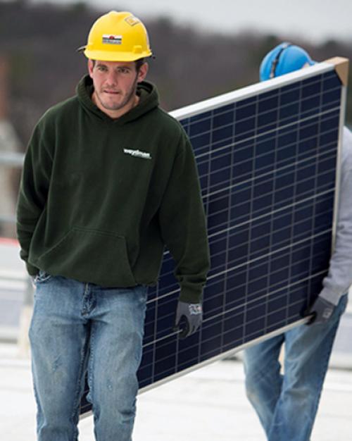 Workers walking with a solar panel