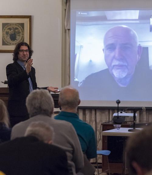 Professor Laurent Dubreuil chats with singer Peter Gabriel on screen.