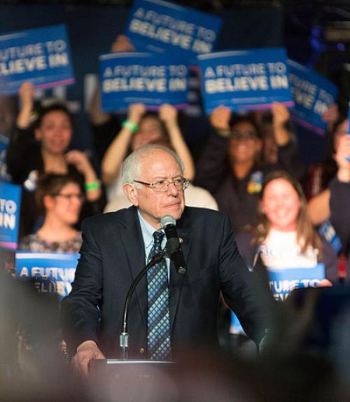  Bernie Sanders in front of supporters holding up signs