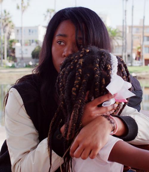  Black woman hugging her daughter in a scene from &quot;From Land to Land&quot; film