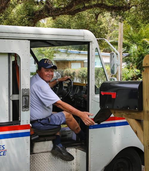 Person in blue uniform opening a mail box