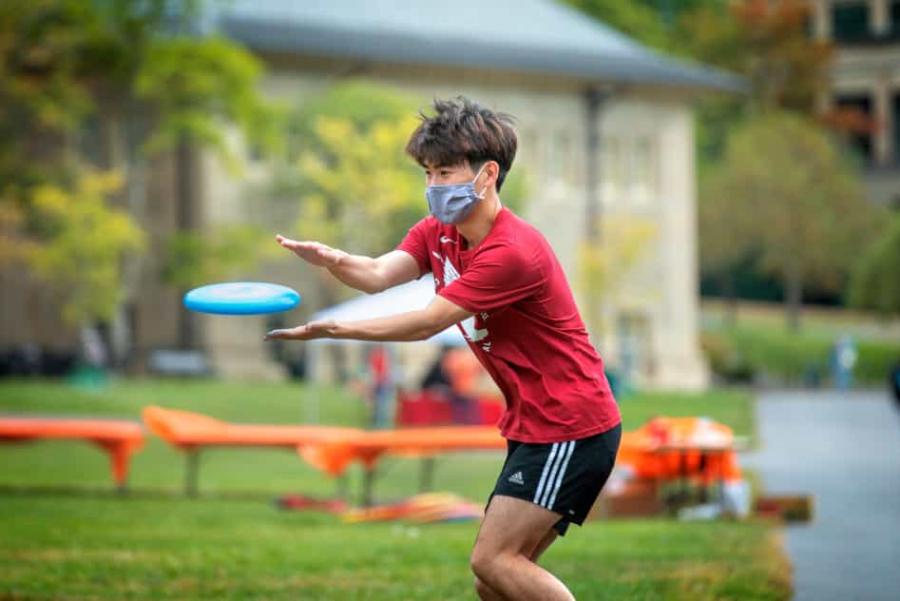 Masked student catches a frisbee