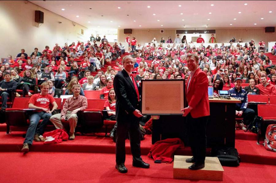 Two people hold a large framed image