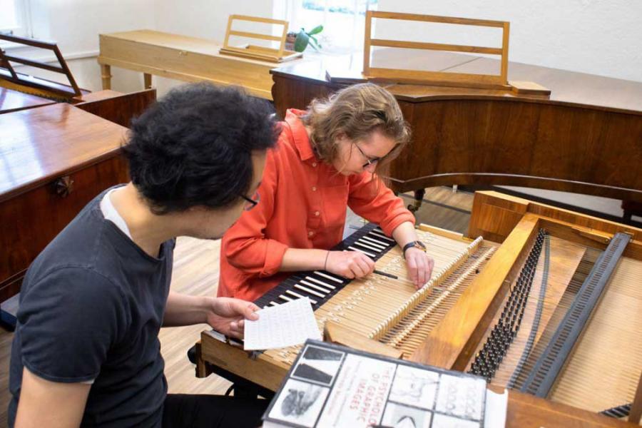 student and professor at piano keyboard