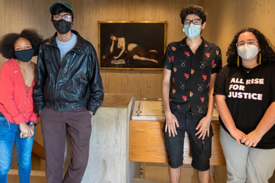 Four people pose near a painting