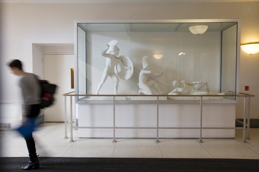 Person walks past a display case containing three figurative sculptures