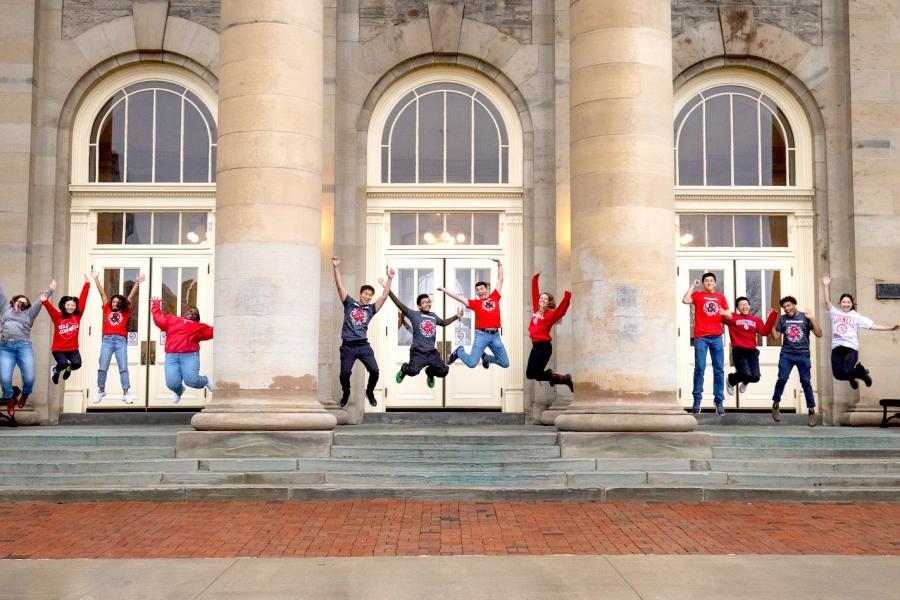 Ambassadors on Goldwin Smith Hall portico jumping