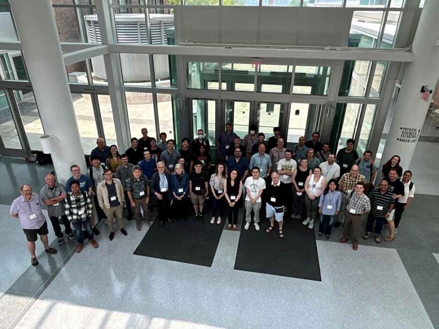 A big group of people wearing conference nametags standing in a semicircle looking up at the camera