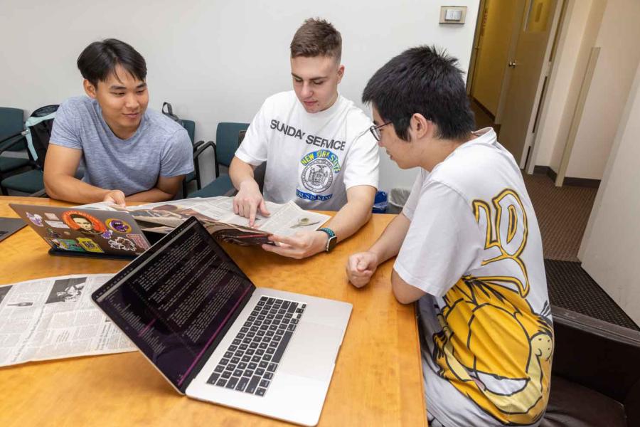 three students look at a newspaper
