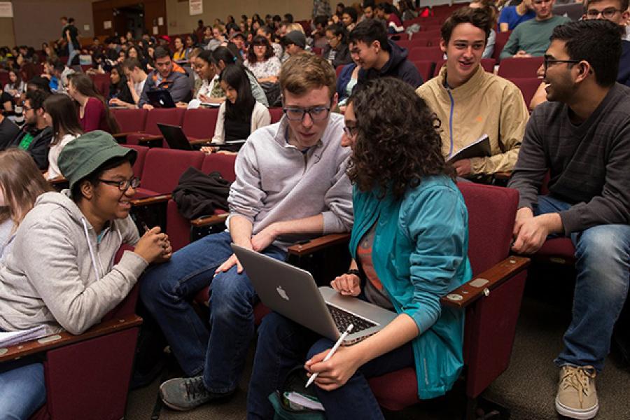 Three students confer over a laptop