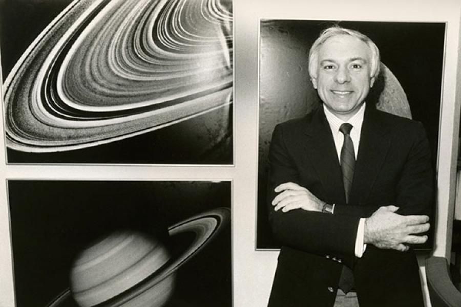 Yervant Terzian standing next to images of Saturn and of Saturn's rings