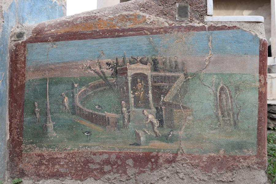 Closeup of one of the paintings from the Casa dell’Efebo dining benches. The painting depicts an Egyptian landscape with a temple (containing a statue of Isis), an obelisk, and a worshipper making offerings at an altar. (Photo: Caitlín Barrett)