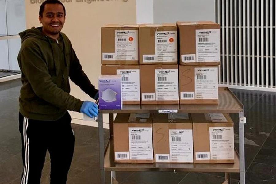 Graduate student pushing cart with boxes of donated supplies on it
