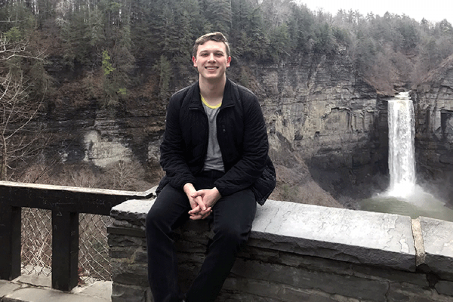 Man smiling in front of a waterfall