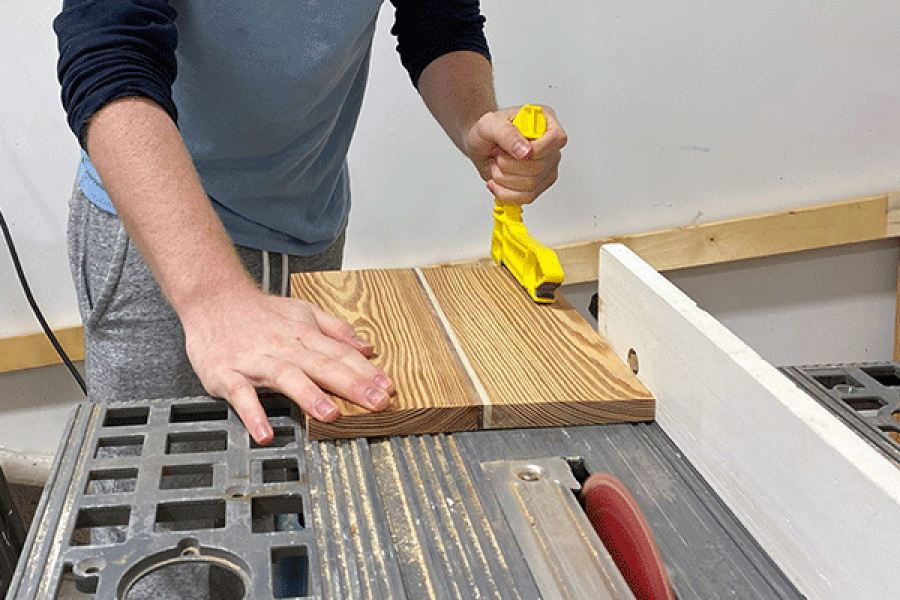 Hands guiding wood through a table saw