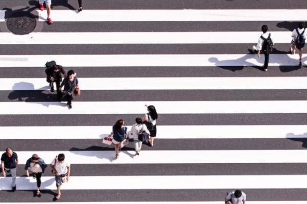 Seen from directly above, 20 people in a striped cross walk