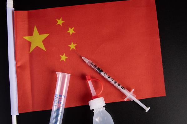 Red flag (of China) with medical syringe and bottle on top of it