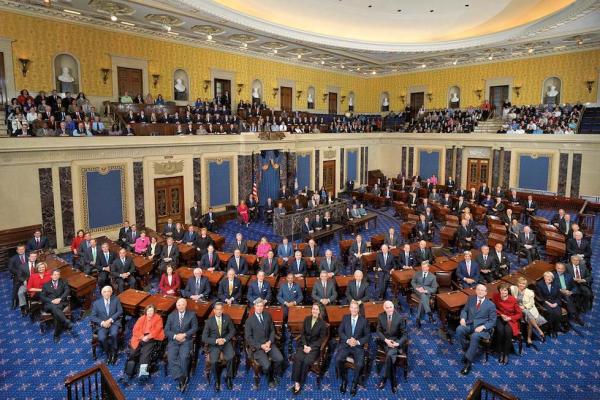 The U.S. Senate chamber (blue carpet, yellow walls) with the Senators seated at their deks