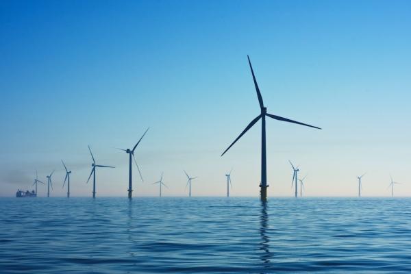 Wind turbines in calm water against a blue dusk sky
