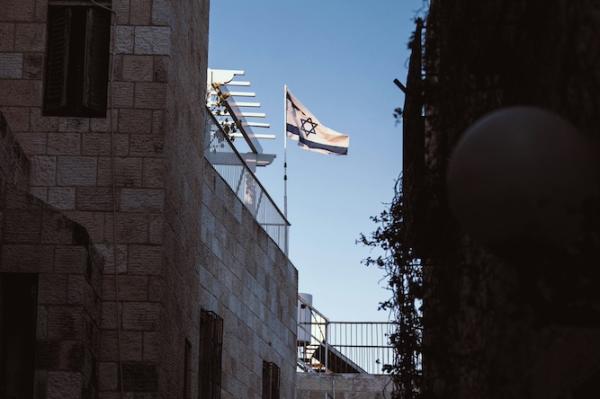 White and blue flag of Israel seen at a distance between two buildings