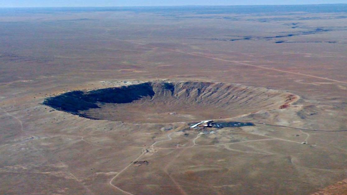 Desert land seen from above, showing a huge crater