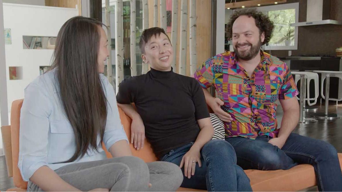 Three people sitting on a couch, laughing