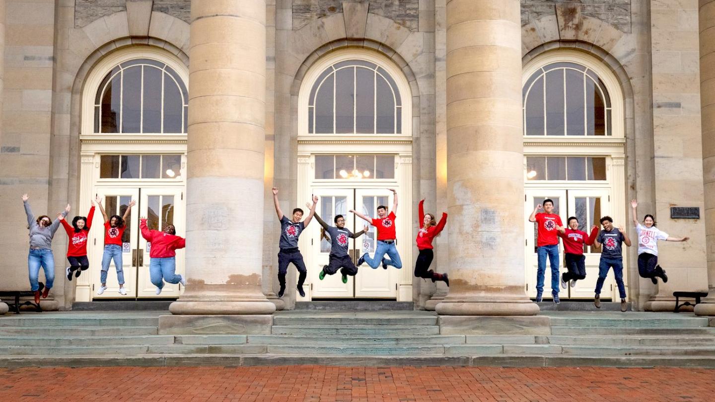 Ambassadors on Goldwin Smith Hall portico jumping