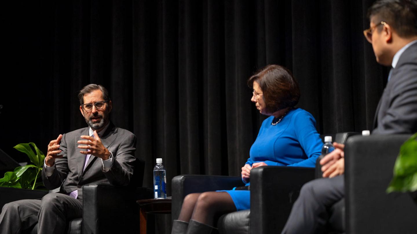 Three people sitting in chairs on a stage