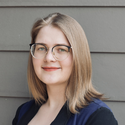 Ekaterina Landgren, long blonde hair and glasses with a blue shirt, smiling