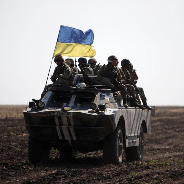 		armored vehicle flying a blue and yellow flage
	