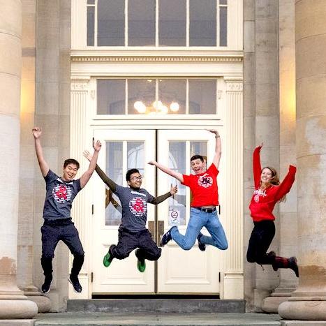 Ambassadors on Goldwin Smith Hall portico jumping
