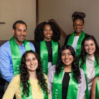 Seven people wearing green honor stoles