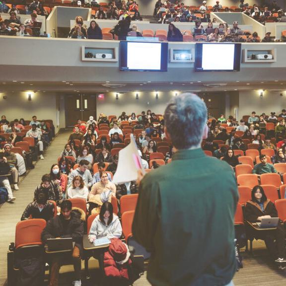 Person stands in front of a mostly full auditorium