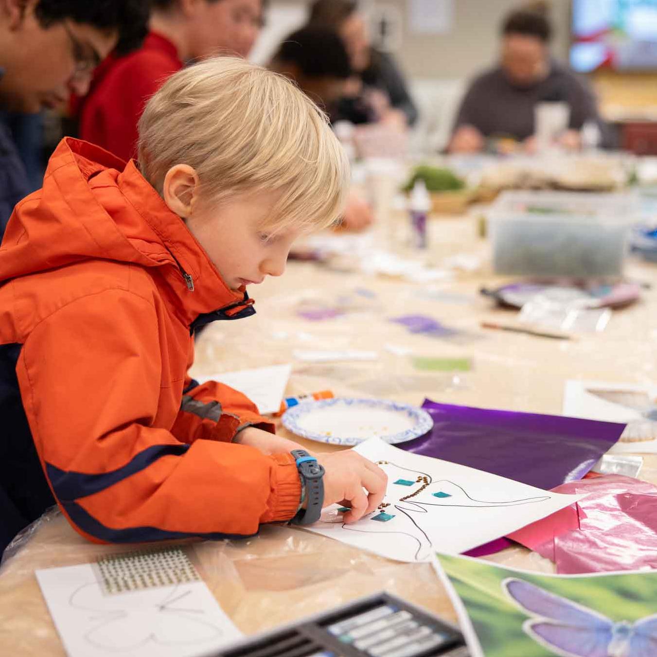 		kid working with art materials to make a butterfly
	