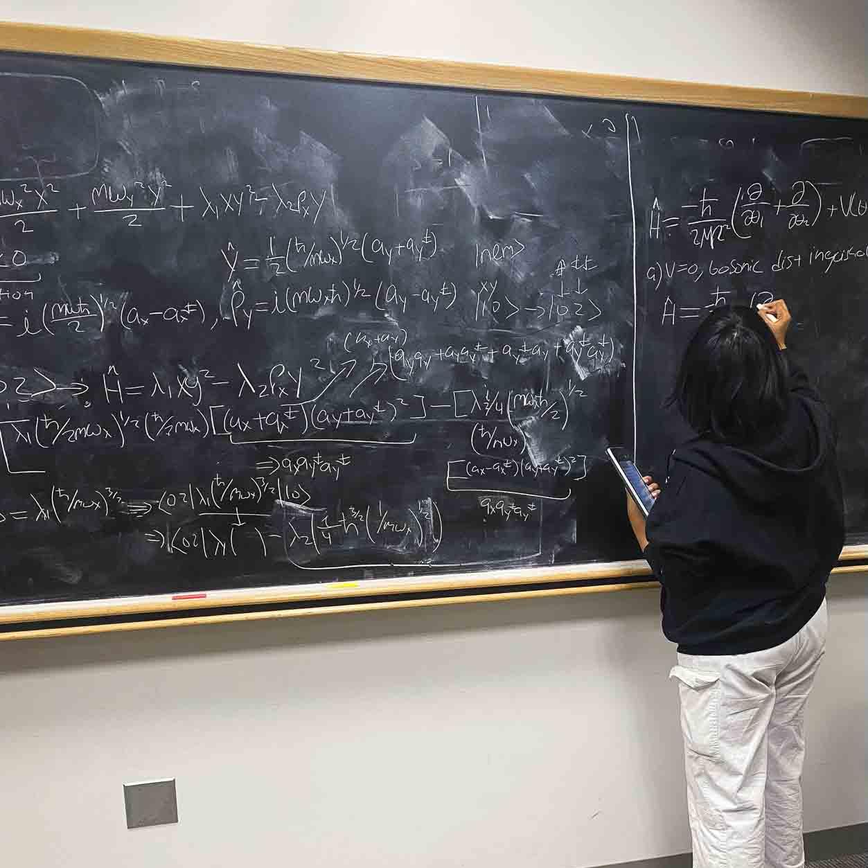 Ariel writing equations on a black board