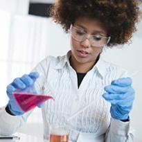 		Person working in a chemistry lab, pouring colored liquid from one beaker to another
	
