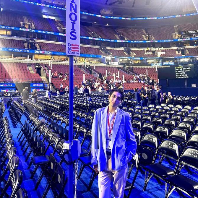 Person standing on the floor an enormous convention center that's mostly empty, next to a banner that says "Illinoi"