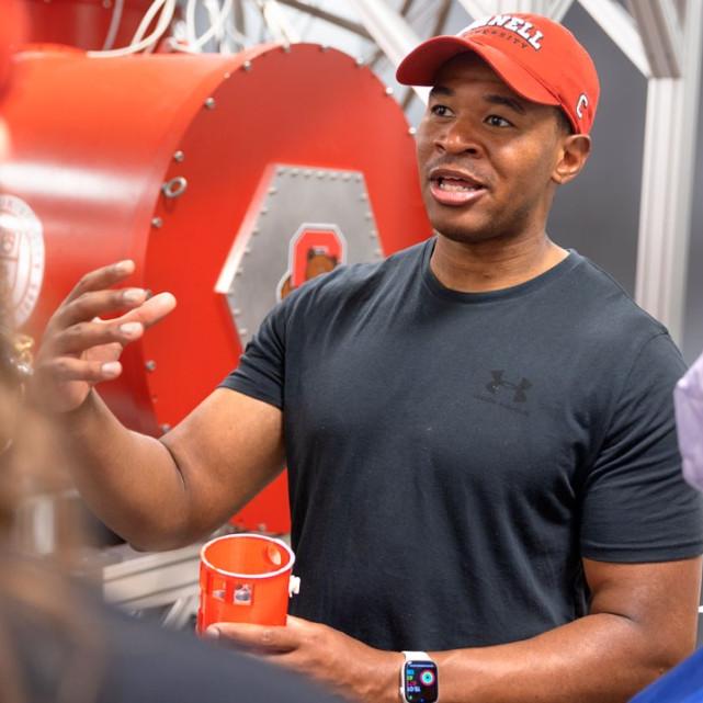 		Person in Cornell cap speaks enthusiastically to a small group
	