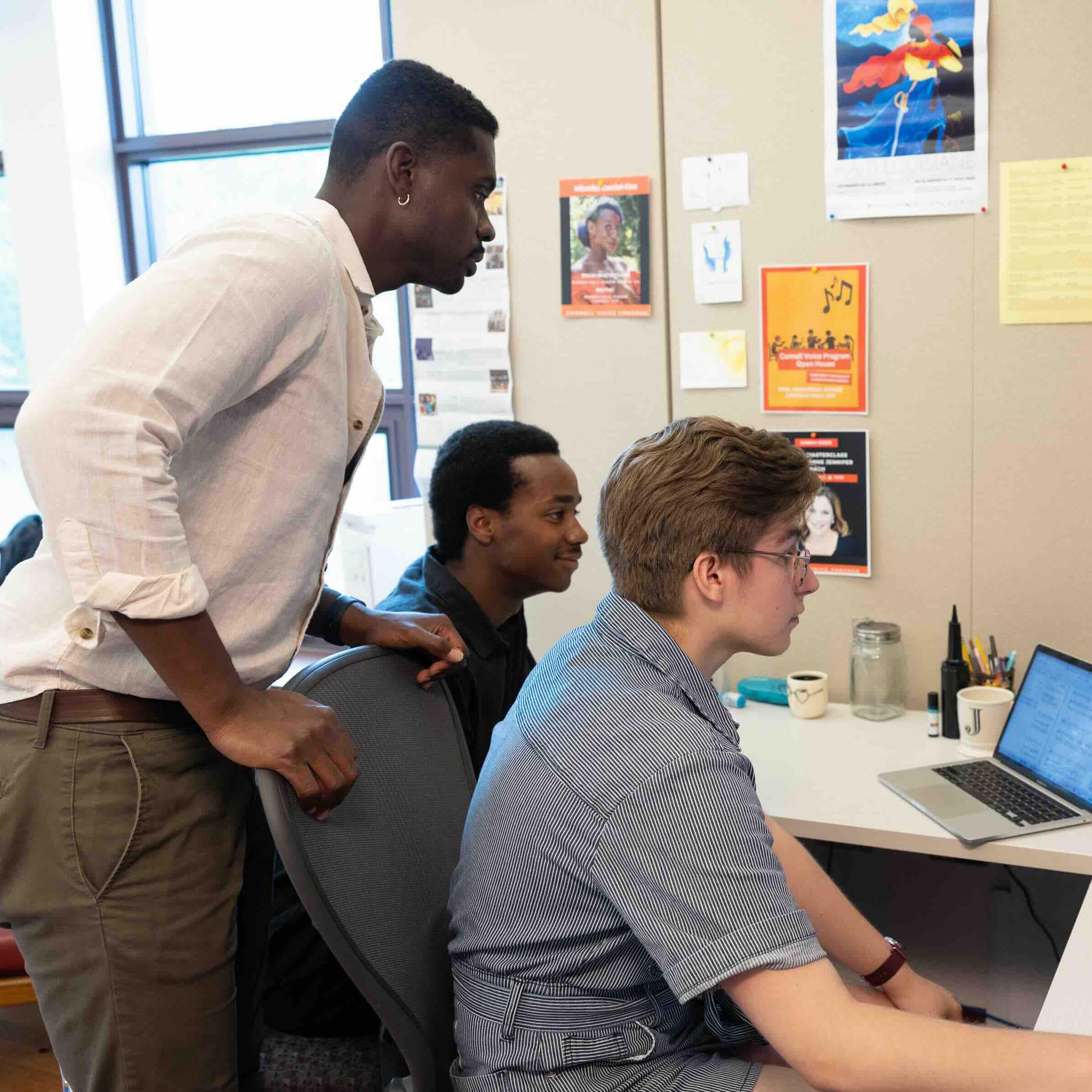 		three people working on a computer
	