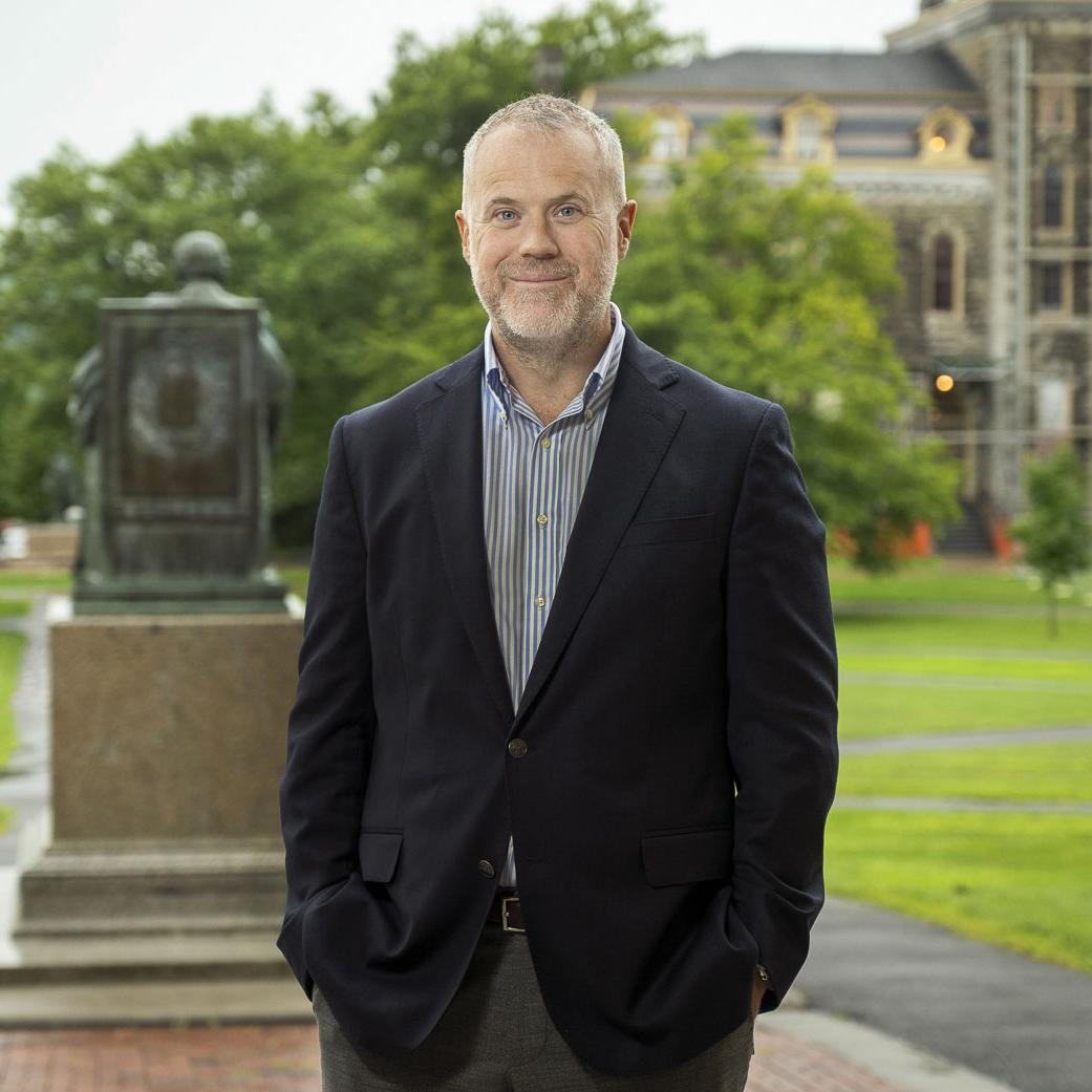 		Dean Peter Loewen posing behind the A.D. White statue on the Arts Quad
	