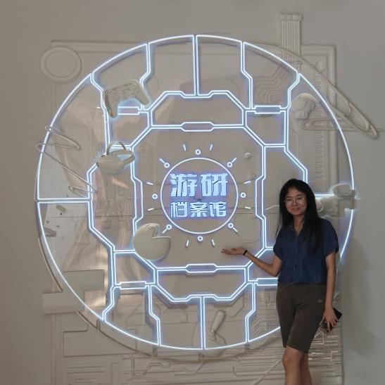 		Person standing in front of a large glowing neon circle outline with Chinese characters in the center
	