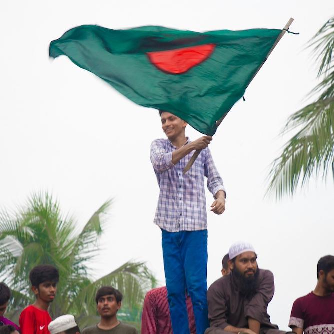 Person waving the green and red flag of Bangladesh