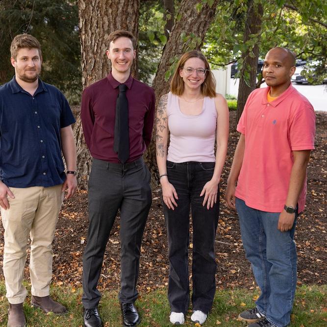 		Five people standing in a line under a tree
	