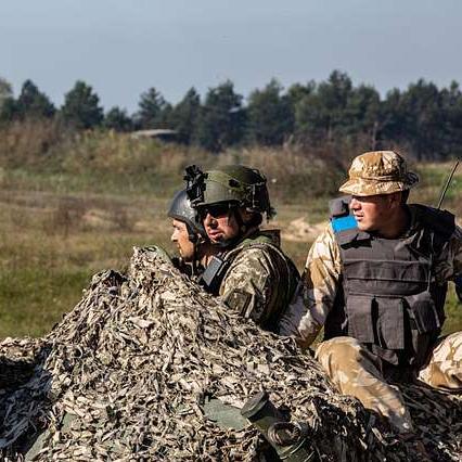 		A few solders in camoflauge in a field
	