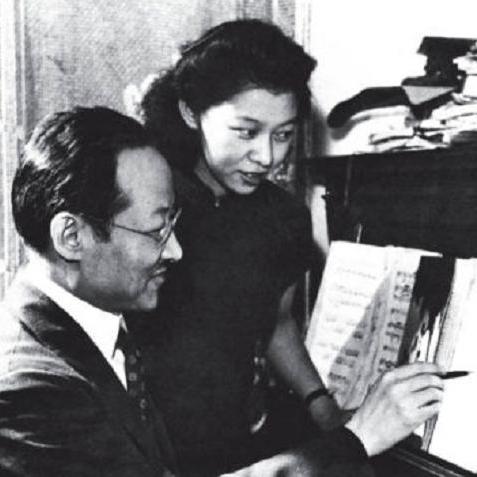 		two people looking at sheet music that's sitting on a piano
	