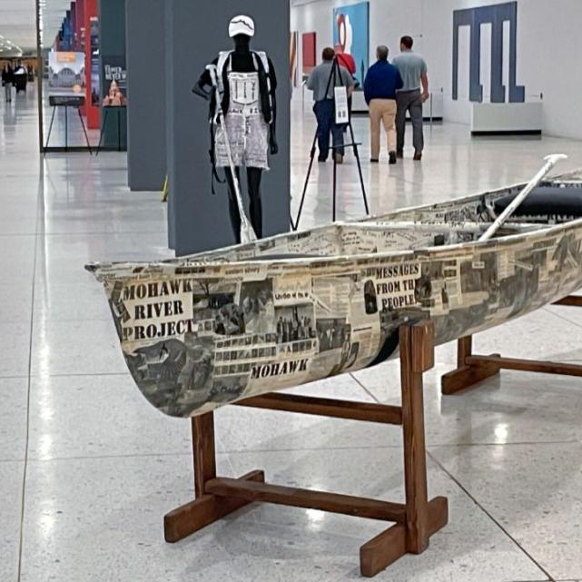 		A canoe covered in written messages, in an exhibit hall
	