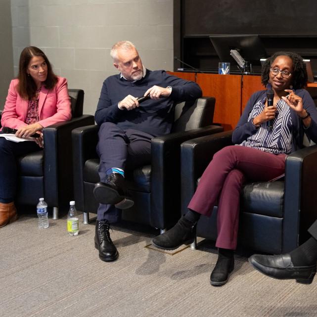 		The panelists sitting in arm chairs, all three looking at Prof. Jamila Michener talking into the microphone.
	