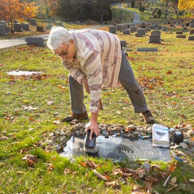 		Person bending over to sweep a flat grave marker
	