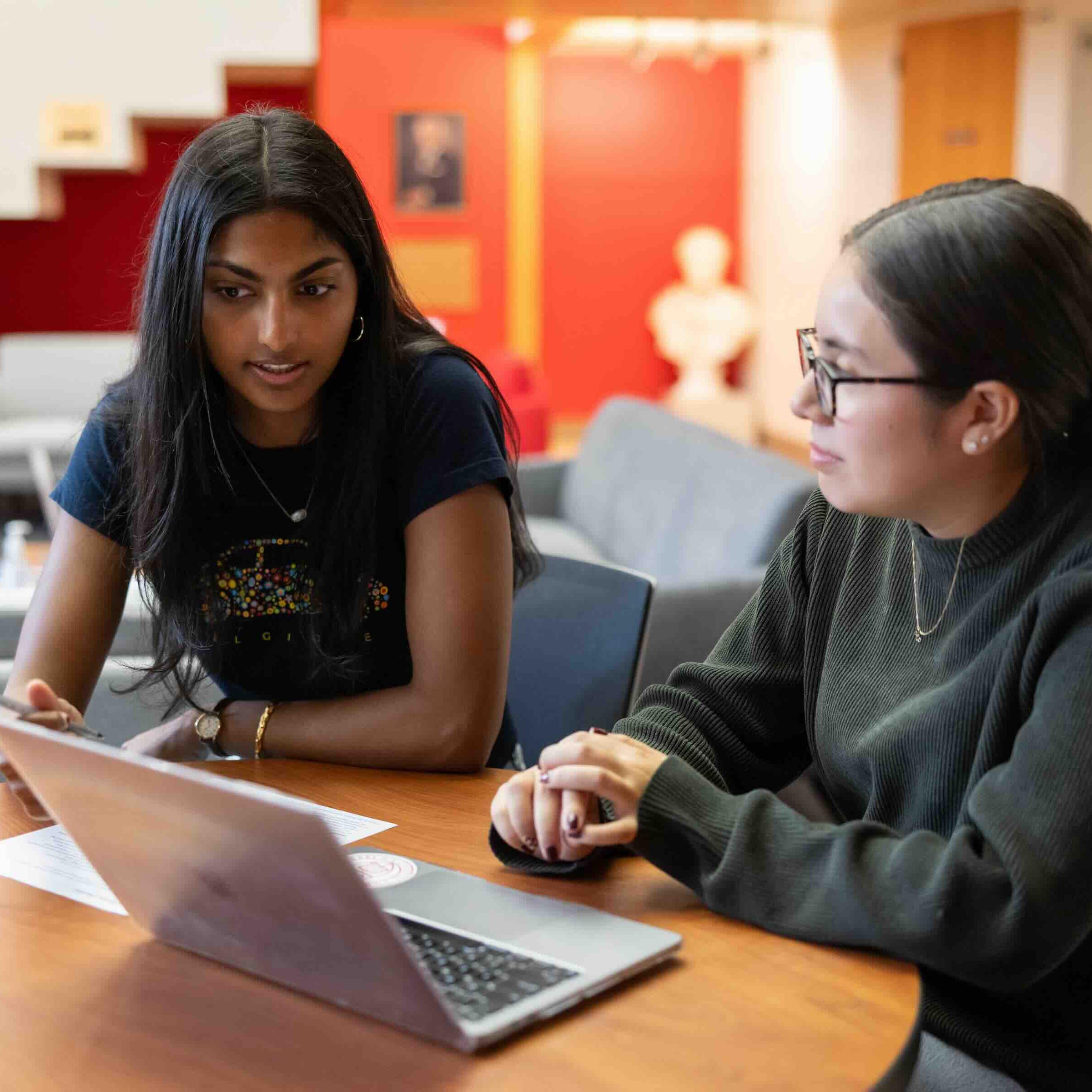 		Two people looking over a text on a computer 
	
